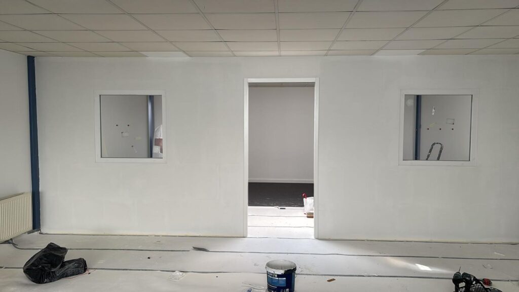 Tussenwand geplaatst in kantoor met ramen en deur met kozijnen